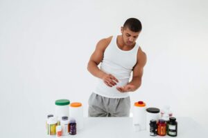 A man is placing creatine pills on a table for his pre-workout routine.